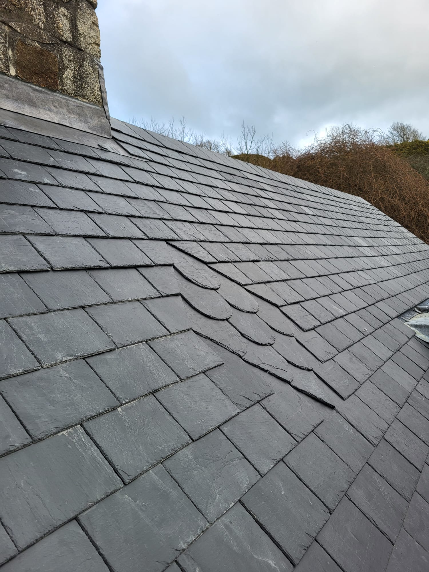 Swept valley with stone chimney on a completed slate roof in Cornwall